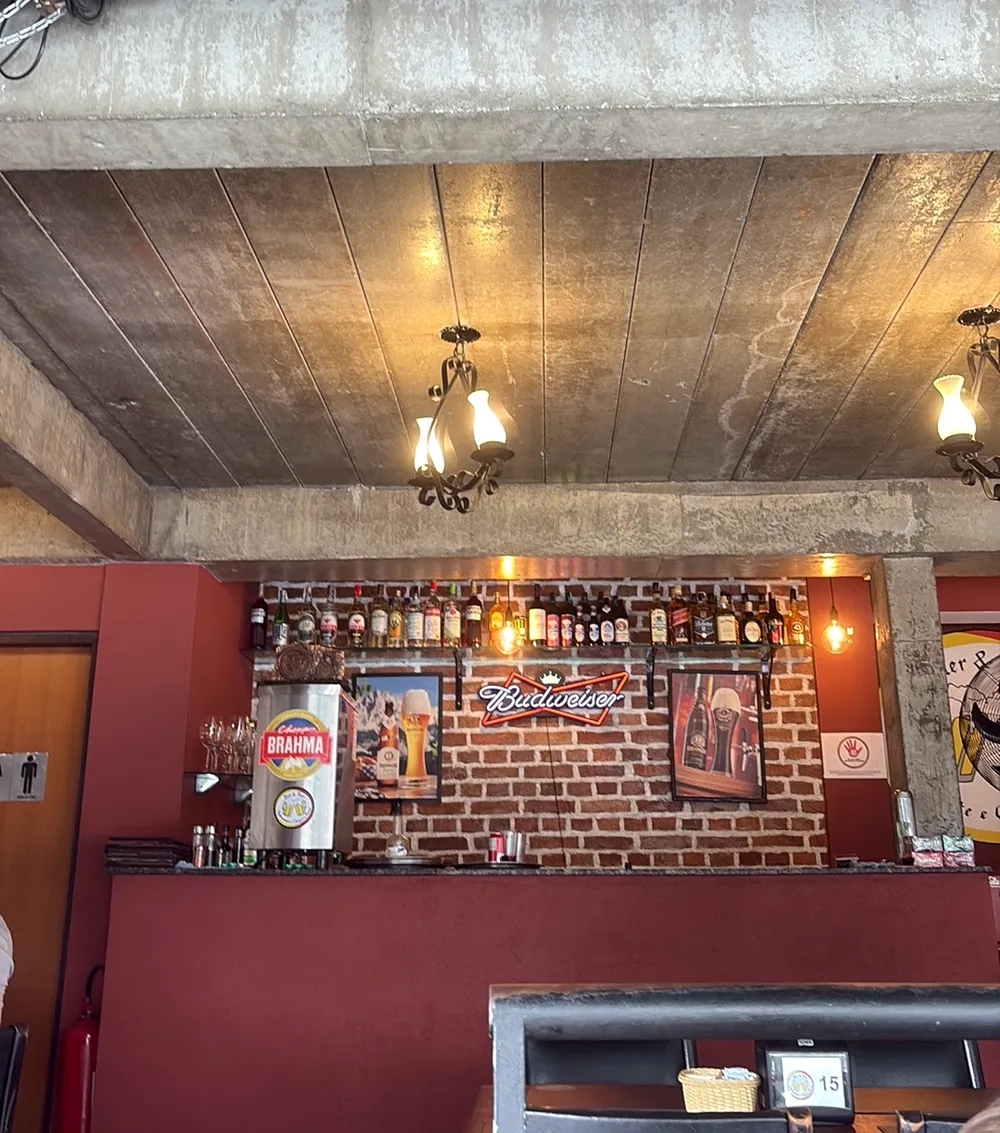 Balcão do bar com parede de tijolos, garrafas e luminárias